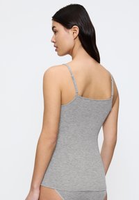 Top aderente grigio con spalline sottili regolabili e una texture liscia e morbida. Nessun motivo o decorazione; design minimalista.