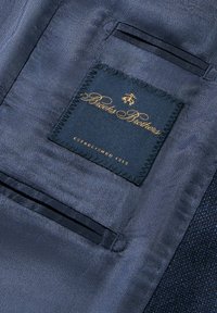 Tessuto blu navy con un design testurizzato, con un'etichetta cucita che riporta "Brooks Brothers" in oro, e un piccolo dettaglio tasca.