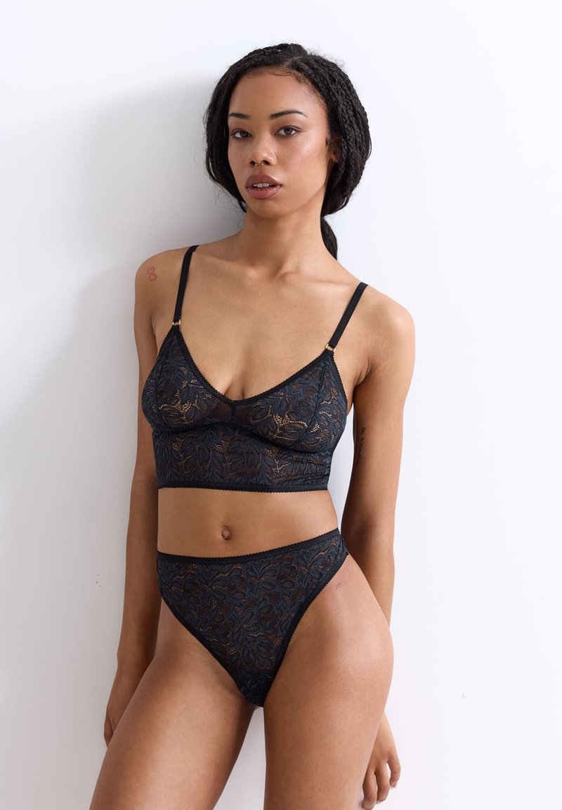 Schwarzer Spitzen-Bralette und dazu passende hochgeschnittene Bikinis, mit floralem Muster, durchsichtiger Textur, verstellbaren Trägern und figurbetontem Design.