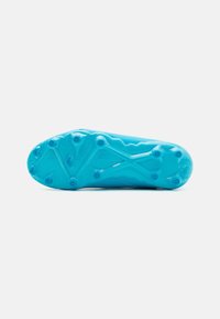 Semelle de chaussures de football turquoise avec une surface texturée et des crampons proéminents pour une meilleure traction. Le design présente un motif de vagues sur l'ensemble.