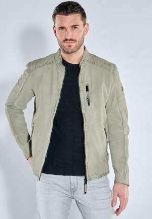 Light gray leather jacket with a bomber design, featuring zippered pockets, textured shoulders, and a slim fit over a black sweater.