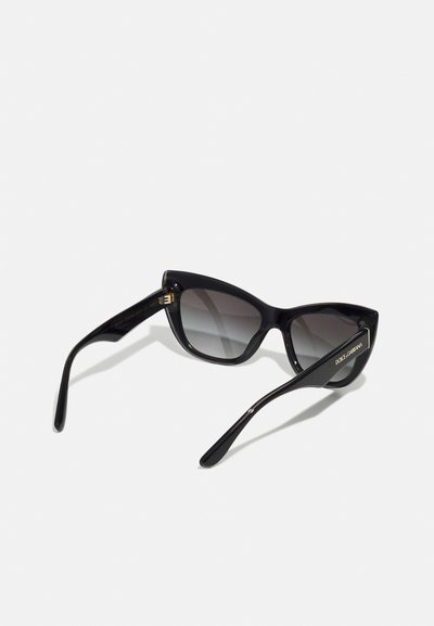 Black cat-eye sunglasses with gradient lenses. Features thick frames and gold accents on the temples, smooth glossy texture.