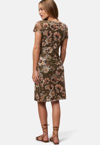 Short, floral dress in olive green with light pink and cream patterns. Short sleeves, fitted shape, and knee-length hem. Brown sandals.