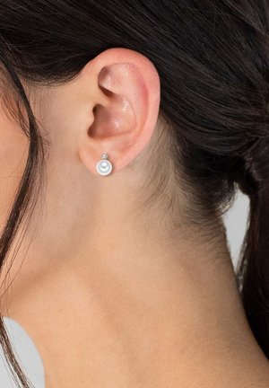 Runde Perlenohrringe mit einem kleinen Zirkonakzent, ausgestattet mit einem glänzenden, silberähnlichen Rücken, vor einem neutralen Hintergrund präsentiert.