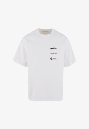 Fehér pamut póló, kerek nyakkivágással, rövid ujjakkal és három fekete nyomtatott logóval: "another." és "Another Cotton Lab".