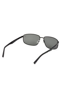 Gafas de sol de metal negro con lentes grises. Forma rectangular, brazos delgados, con un diseño minimalista y almohadillas nasales transparentes.