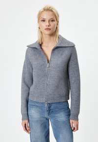 Grå ribbet zip-sweater med bred krave og tætsiddende kropsform. Har lange ærmer og en cropped længde, lavet af et blødt strikket materiale.
