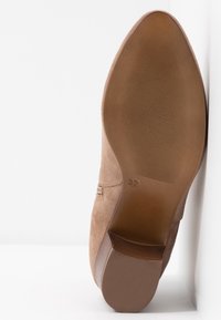 Semelle d'une chaussure beige en daim à bout pointu avec une semelle antidérapante texturée, un petit talon et la taille 37 marquée sur la semelle.