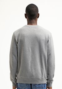 Sweatshirt gris à manches longues et à poignets côtelés. Présente un col rond et une texture lisse. Design simple et classique.