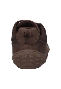 Chaussure de sport marron avec une semelle en caoutchouc texturée, un dessus en tissu doux et une languette au talon pour un enfilage facile.
