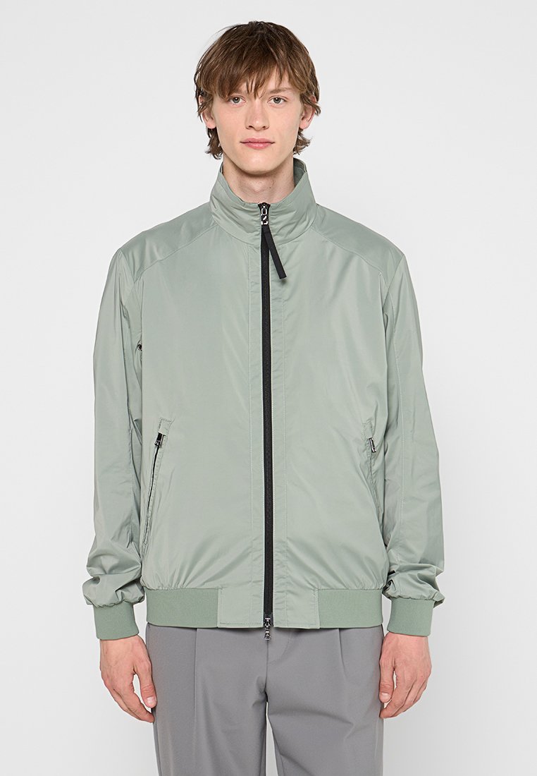 Hellgrüne Bomberjacke mit Stehkragen, schwarzem Reißverschluss, seitlichen Taschen, elastischen Bündchen und Saum; glattes, leichtes Material.