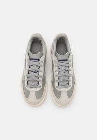 Szare trampki wykonane z zamszu i skóry, z szarymi sznurówkami, teksturowanym językiem oraz kremową gumową podeszwą.