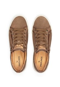 Zapatillas de cuero marrón con parte superior texturizada, puntera redonda, suela de goma blanca en contraste y detalle decorativo de cremallera lateral.