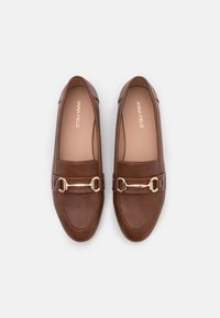 Mocasines de cuero marrón con un acabado suave, que presentan un detalle en cadena en tono dorado a lo largo del antepié y una punta en forma de almendra.