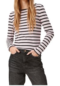 Maglietta a maniche lunghe aderente di un rosa chiaro con strisce orizzontali nere, texture a coste, scollatura rotonda, abbinata a jeans neri a vita alta.