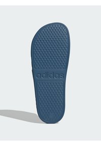 Adidas plava guma sandala s đonom koji ima teksturirani, točkasti uzorak s utisnutim nazivom branda blizu pete. Glatke ivice.