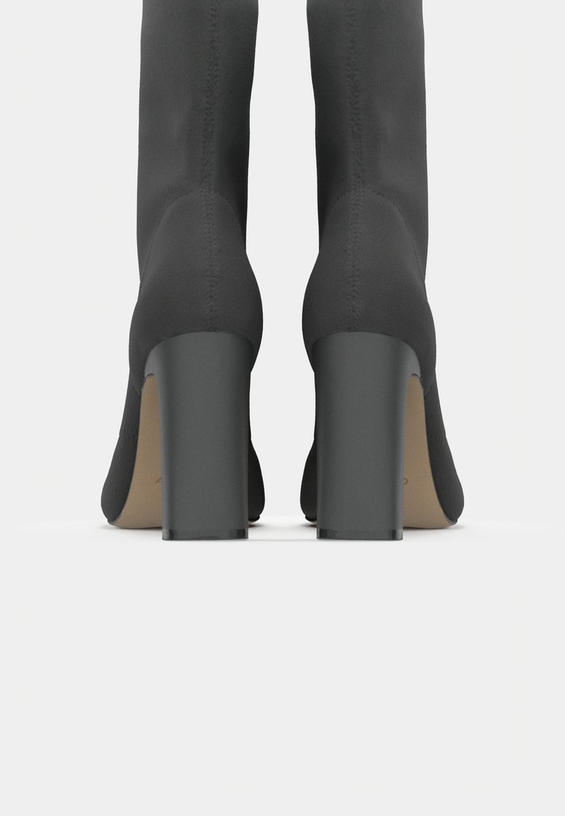 Schwarze High Heel Stiefel mit einer glatten Stoffoberfläche, abgerundetem Zeh und breiten quadratischenabsätzen, die vertikale Nahtdetails am Schaft aufweisen.