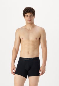 Sorte boxer briefs med en mærket talje. Glat bomuldsmateriale og tætsiddende design. Modellen er obervabeløs og viser briefsene frem.