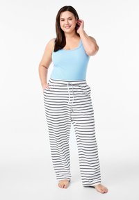 Top sin mangas azul claro con canalé y bordado de encaje, combinado con pantalones de descanso blancos que presentan rayas negras horizontales y bolsillos laterales.