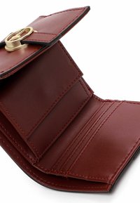 Raudonas sintetinės odos piniginė su auksiniu užsegimu, keliais kortelių laikikliais ir kontrastinėmis juodomis briaunomis. Lygi tekstūra su minimalia dizaino koncepcija.