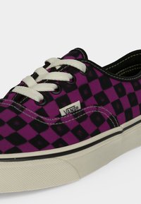 Нисък модел маратонки Vans с лилаво-черен шахматен десен, бели връзки и бяла гумена подметка с черна ивица.