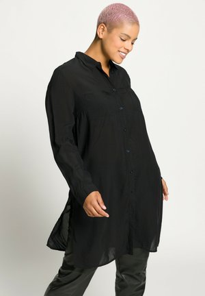 Black button-up shirt made of lightweight fabric, featuring long sleeves, a collar, and two chest pockets; relaxed fit with a longer back.