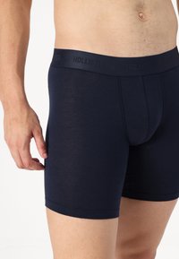 Marineblaue Baumwollboxershorts mit einem elastischen Bund mit Markenlogo. Figurbetontes Design, glatte Textur und mittlere Beinlänge.
