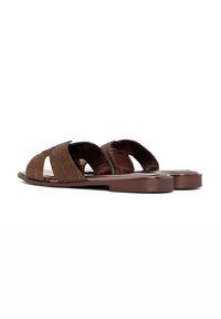 Sandales plates tressées marron avec un design à bout ouvert, comprenant deux larges bretelles et une semelle plate. Tissu texturé et finition lisse.