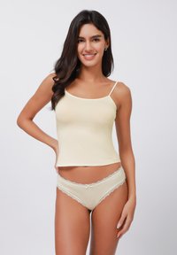 Light yellow camisole with thin straps and fitted design, paired with matching lace-trimmed briefs in a similar shade. Smooth texture.