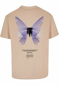 Beige t-shirt med et stort violet sommerfugle grafik på ryggen, med et sort logo og trykt tekst nedenunder. Korte ærmer, rund halsudskæring.