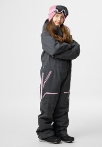 Grijs sk Suit met roze ritsen en accenten, voorzien van een capuchon, meerdere ritszakken en een roze muts met goggles. Zwarte schoenen.