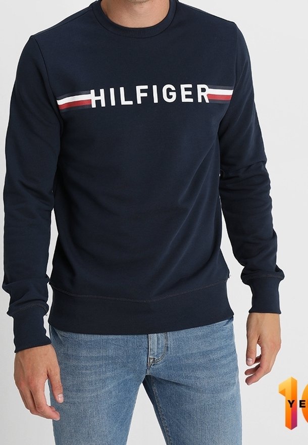 Sudadera azul marino con letras blancas "HILFIGER" y franjas rojas y blancas en el pecho. Puños y dobladillo acanalados, textura suave.