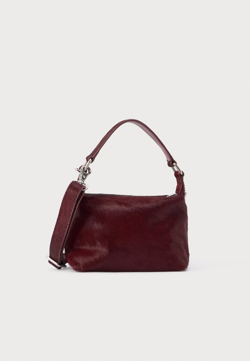 Malá obdélníková kabelka barvy burgundské s texturovaným povrchem, krátkým madlem a odnímatelným ramenním popruhem na čistém světlém pozadí.