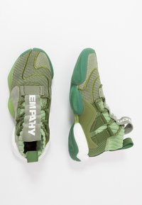 Zielone buty sportowe z teksturowaną dzianinową cholewką, gumową podeszwą oraz wyraźną etykietą 'EMPATHY'. Wyposażone w pętelki i paski zapewniające pewne dopasowanie.