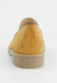 Gelbe Wildlederschuhe mit abgerundeter Ferse und einer strukturierten beigen Sohle, die an den Nähten dezente Stickdetails aufweisen.