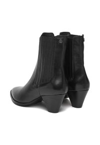 Cizme de glezna din piele neagră, cu vârful rotund, panouri laterale elastice și un toc jos, stivuit. Textură netedă, cu detalii minime.