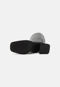 Gray ankle boot featuring a smooth textile upper, black rubber sole with a flat heel, and a textured surface for grip.