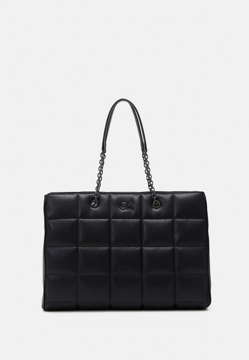 Black quilted handbag made of leather with a rectangular shape, featuring chain handles and embossed logo on the front.
