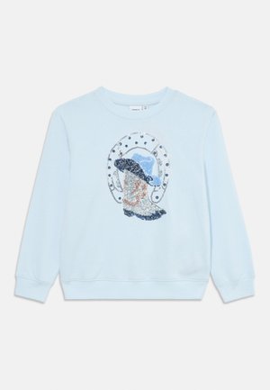 Light blue sweatshirt featuring a decorative design of a hat and sequins in silver, blue, and peach colors. Long sleeves and ribbed cuffs.