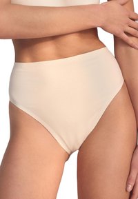 Biancheria intima a vita alta, color beige chiaro, realizzata in tessuto liscio ed elastico con design senza cuciture, caratterizzata da un taglio pulito e minimalista.