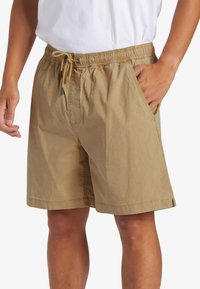 Khaki šortky vyrobené z lehkého materiálu; mají elastický pas se šňůrkou, boční kapsy a uvolněný střih.