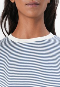 Tricou cu guler rotund, cu dungi albastre și albe orizontale, având un guler alb contrastant. Material moale cu o textură netedă.