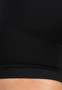 Schwarze nahtlose Stoffshorts mit glatter Textur und taillierter Passform. Mit einem kontrastierenden matten Band entlang der Taille.
