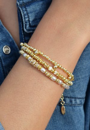 Armband aus goldenen Perlen mit mehreren Strängen, glänzenden Kugelperlen und weißen Perlen. Ein Strang enthält klare Strasssteine für zusätzlichen Detailreichtum.