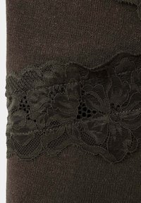 Tissu tricoté marron foncé avec une bande horizontale de dentelle florale présentant des motifs complexes en maille et en fleurs.