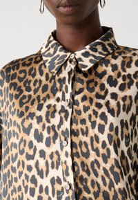 Leopardprint skjorte med en silkeblød tekstur, klassisk krave, skjult knaplukning og dekorative knapper i sølvfarve.