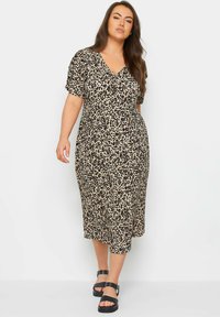 Midi dress with leopard print in beige and black; short, puffed sleeves; v-neckline; made of soft fabric; paired with chunky black sandals.