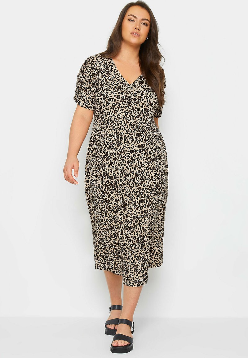 Midi dress with leopard print in beige and black; short, puffed sleeves; v-neckline; made of soft fabric; paired with chunky black sandals.