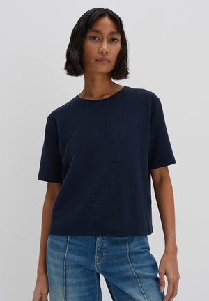 T-shirt blu navy a maniche corte con un motivo testurizzato, scollatura rotonda e vestibilità rilassata. Abbinato a jeans blu scoloriti.