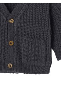 Grau gestrickte Strickjacke mit strukturiertem Design, fünf Messingknöpfen und einer aufgesetzten Tasche auf der Vorderseite. Hergestellt aus dickem Garn.